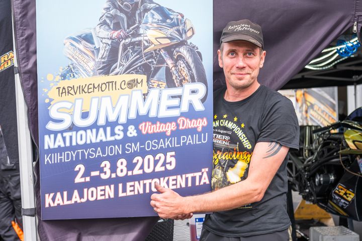Mies pitelee kilpa-autotapahtuman mainosjulistetta.