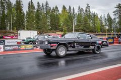 Auto kiihdytyskilpailussa radalla, taustalla metsä ja toisia autoja.