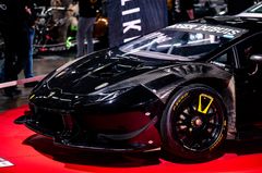 Punaisella alustalla esillä oleva musta superauto näyttelyssä.