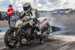 Henkilö moottoripyöräkisassa lähdössä liikkeelle, savua nousee takarenkaasta.