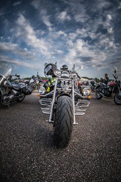 Moottoripyörä etualalla pysäköitynä, taustalla useita muita moottoripyöriä.