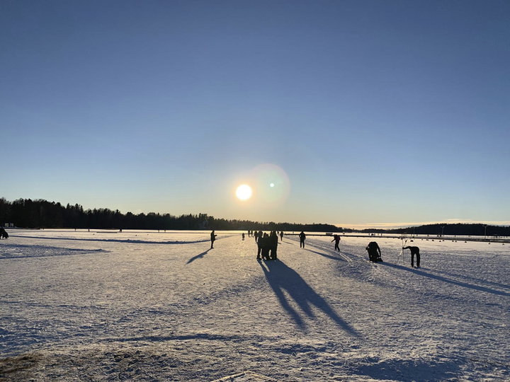 Talvimaisema Aurlahden rannasta. Ihmisiä kävelle jäällä.