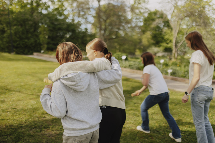 Lapsia pihalla. Etualalla olevat tytöt kulkevat kädet toistensa olalla.