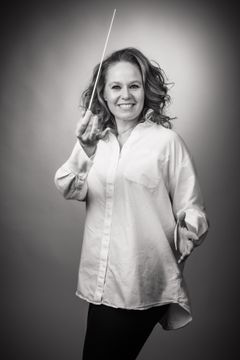 "Kapellimestari johtaa orkesteria ja pitää tahtipuikkoa."