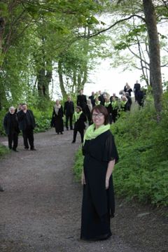 Paikallisia laulajia luonnon ympäröimänä, pukeutuneina mustiin asuihin ja vihreisiin huiveihin.