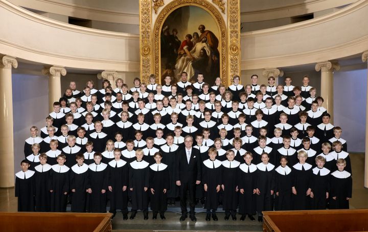 Nuorten poikakuoro laulamassa yhdessä perinteisessä konserttisalissa.