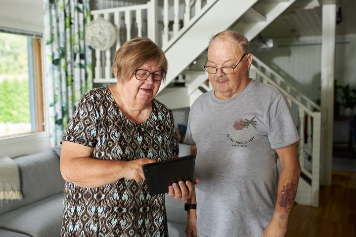 Ikääntynyt pariskunta katsoo yhdessä tablettia.