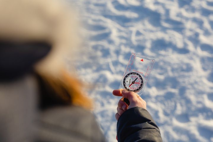 Henkilö lumisessa maastossa pitää kompassia kädessään.