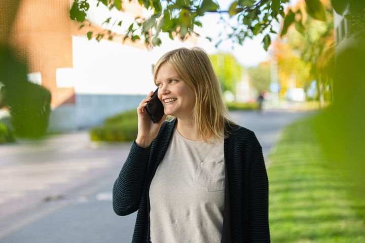 Nainen puhuu iloisesti puhelimeen.