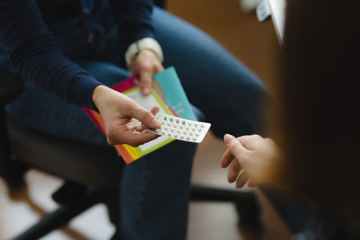 Kaksi henkilöä, joista toinen antaa toiselle pilleriliuskan.