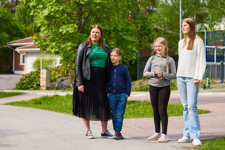 Ihmisryhmä seisoo ulkona kesäisenä päivänä vehreässä ympäristössä.