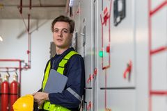 Henkilö turvavarusteissa seisoo teollisessa ympäristössä pitäen kypärää ja tablettia.