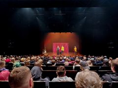 Salillinen nuoria katsomassa lavalla olevia esiintyjiä.