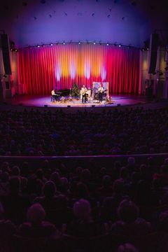 Konserttiesitys Turun Konserttitalon lavalla värikkäiden valojen loisteessa.