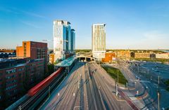 Taka-alalla Kauppakeskus Redi ja sen tornit sekä junatien metrosilta ja Itäväylä etualalla.