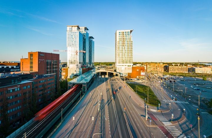 Taka-alalla Kauppakeskus Redi ja sen tornit sekä junatien metrosilta ja Itäväylä etualalla.