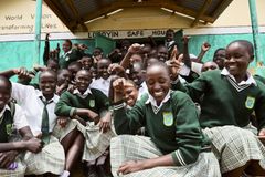 Ryhmä nuoria tyttöjä koulupuvuissa istuu ja seisoo ulkona portailla, iloisina ja hymyilevinä.