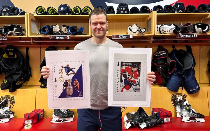 Aleksander Barkov ja suurennokset Postimerkeistään, käsissään valokuvan vasemmassa laidassa 12.04.2025 julkaistava ja oikeassa laidassa 12.04.2019 julkaistu merkki.