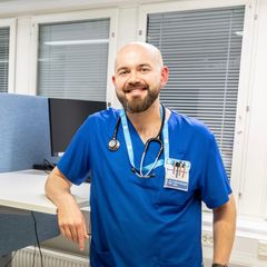 "Nuori lääkäri hymyilee kameralle sairaalan toimistossa."