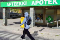 Takaapäin kuvattu henkilö kulkee apteekin ohitse.