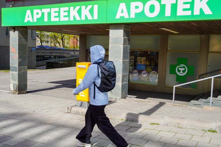 Takaapäin kuvattu henkilö kulkee apteekin ohitse.