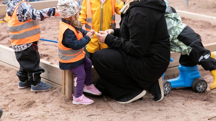 Lapset hoitajan kanssa päiväkodin pihalla.