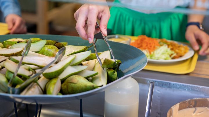 Ihminen ottamassa päärynöitä ruokalinjastolla.