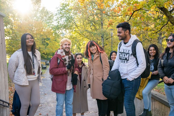 Ryhmä opiskelijoita kampuksella syksyisessä maisemassa
