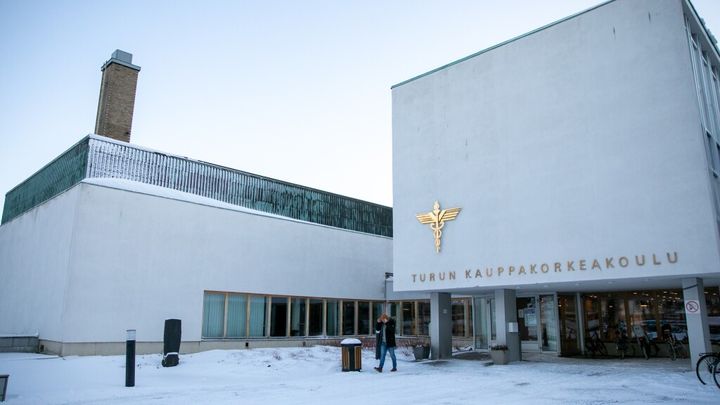 Henkilö kävelee Turun kauppakorkeakoulun pääsisäänkäynnin edessä talvella.