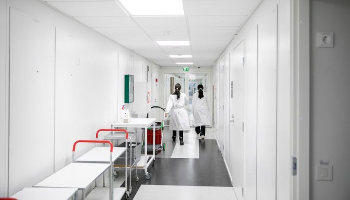 Kaksi valkotakkista ihmistä kävelee käytävällä.