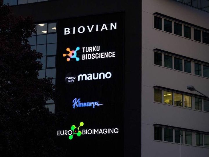 Pimeällä otettu kuva BioCityn seinän logoista, joissa myös Euro-BioImagingin logo