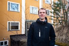 Tutkija kuvattuna ulkona keltaisen kerrostalon edustalla