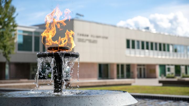 Turun yliopiston päärakennus ja aukion suihkulähteessä palava tuli.