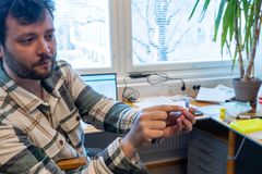 Tutkijalla on kädessään näyteputki, jonka sisällä näkyy kookas verta imenyt punkki