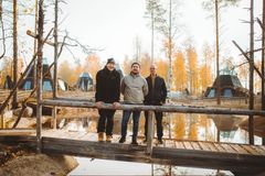 Apukka Resortin perustajaosakkaat Markus Kolari, Miika Sorvari ja Harri Mällinen puisella sillalla seisomassa luontomaisemassa