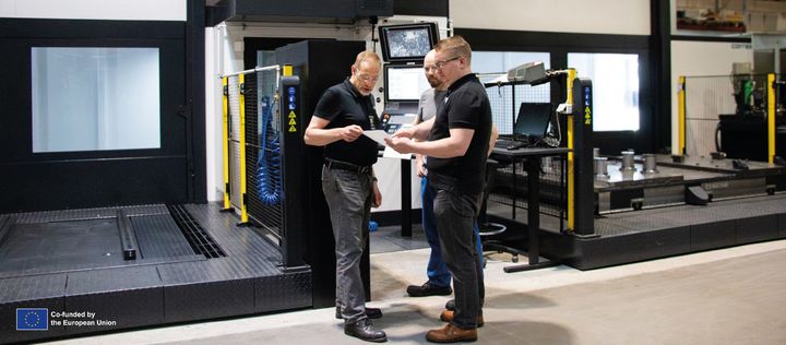 Liiketoimintajohtaja Mika Luopajärvi, koneistaja Timo Syrjälä ja komponenttivalmistuksen päällikkö Johannes Tyni uuden Correa-portaalijyrsinkoneen edustalla. Kone laskee Finn-Power-puristimen rungon tuotantoajan jopa kolmannekseen entisestä.