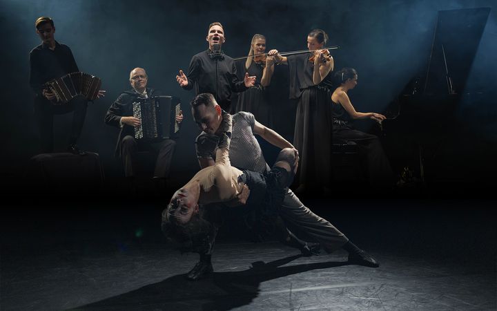 Tanssija- ja muusikkoryhmä esiintyy lavalla tunnelmallisessa valaistuksessa.