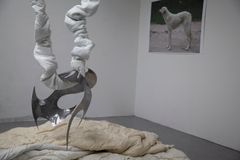 Sculpture made of fabric and metal resembling a suspended figure, with a dog photo on the wall.