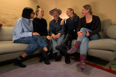 Työryhmän jäseniä istumassa sohvalla iloisesti keskustellen.