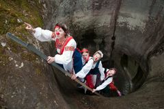 Kuvassa kuilusta nousee neljä klovnia kansallispuvut päällään.