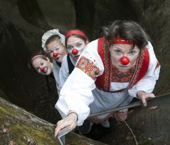 Kuvassa neljä klovnia kiipeää tikkailla kuilusta