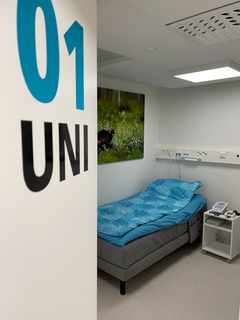 Itä-Suomen yliopiston SmartSleep-laboratorion unihuone, jossa sekä referenssi- että ElvySense-laitteistoja yöpöydällä. ElvySense anturi on petauspatjan alla eikä näy kuvassa.