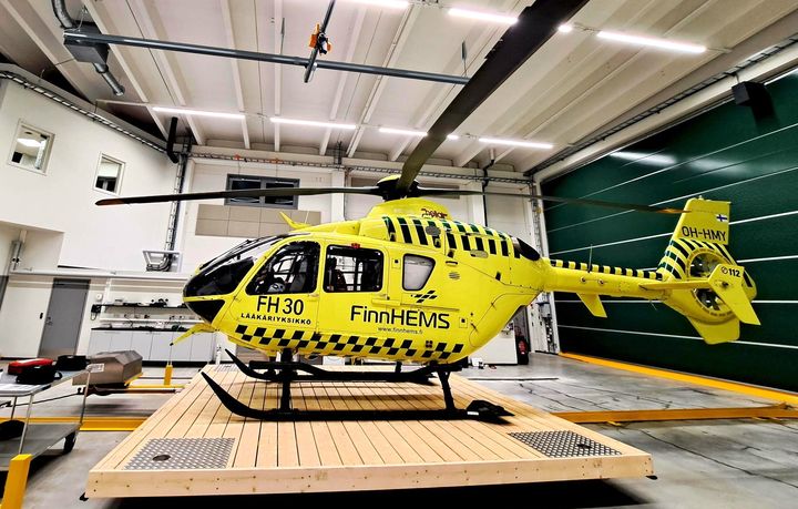 Keltainen FinnHEMS-lääkärihelikopteri sisätiloissa helikopterihallissa
