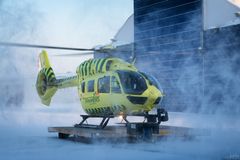 Keltainen Airbus H145-lääkintähelikopteri seisoo Rovaniemen tukikohdan pihalla lumituiskussa