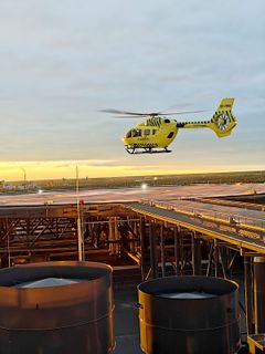 Keltainen lääkintähelikopteri laskeutuu OYSin kattokentälle ilta-auringon aikaan