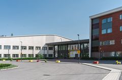 Kuvassa suuri rakennus, jonka vaalea kaksikerroksinen osa yhdistyy korkeampaan punatiiliseen osaan keskellä sijaitsevan matalamman yhdysrakennuksen kautta. Keskellä rakennusta pääovi, jonka vieressä keltainen logopallo ja suurella teksti Valteri.