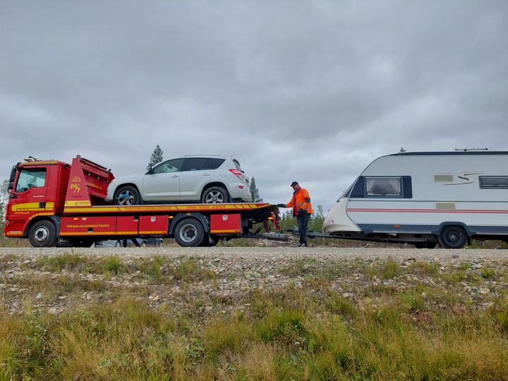 Viking%20hinausauto%2C%20jonka%20lavalla%20hopeinen%20henkil%F6auto%20ja%20hinausauton%20per%E4ss%E4%20asuntovaunu%20tien%20varrella.
