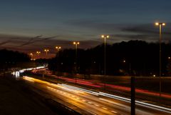 Katuvalot loistavat moottoritien yllä iltahämärässä.