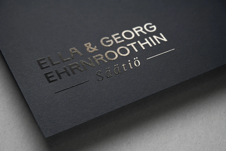 Svart kort med texten "ELLA & GEORG EHRNROOTHIN Säätiö" i guld.