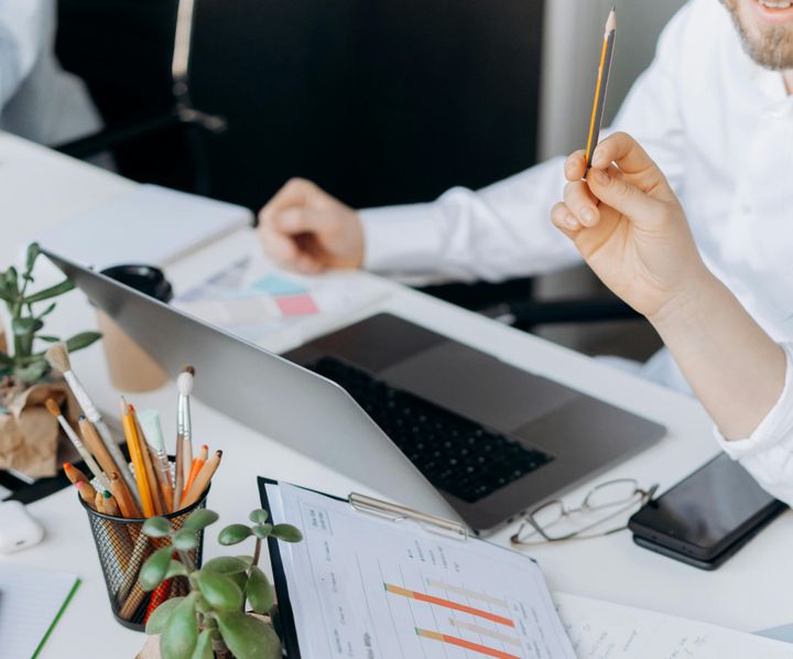 Toimistolla kannettavan tietokoneen äärellä tilastoja ja ihmisiä työskentelemässä.